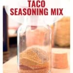 A glass jar filled with layered spices, labeled Homemade Taco Seasoning Mix.