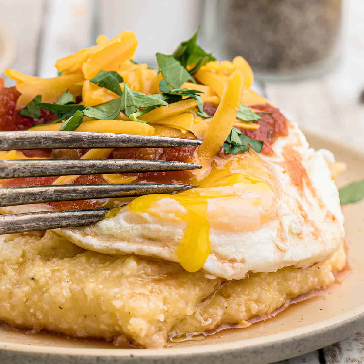 Huevos and Grits - Grits Rancheros - on a white plate with a fork.