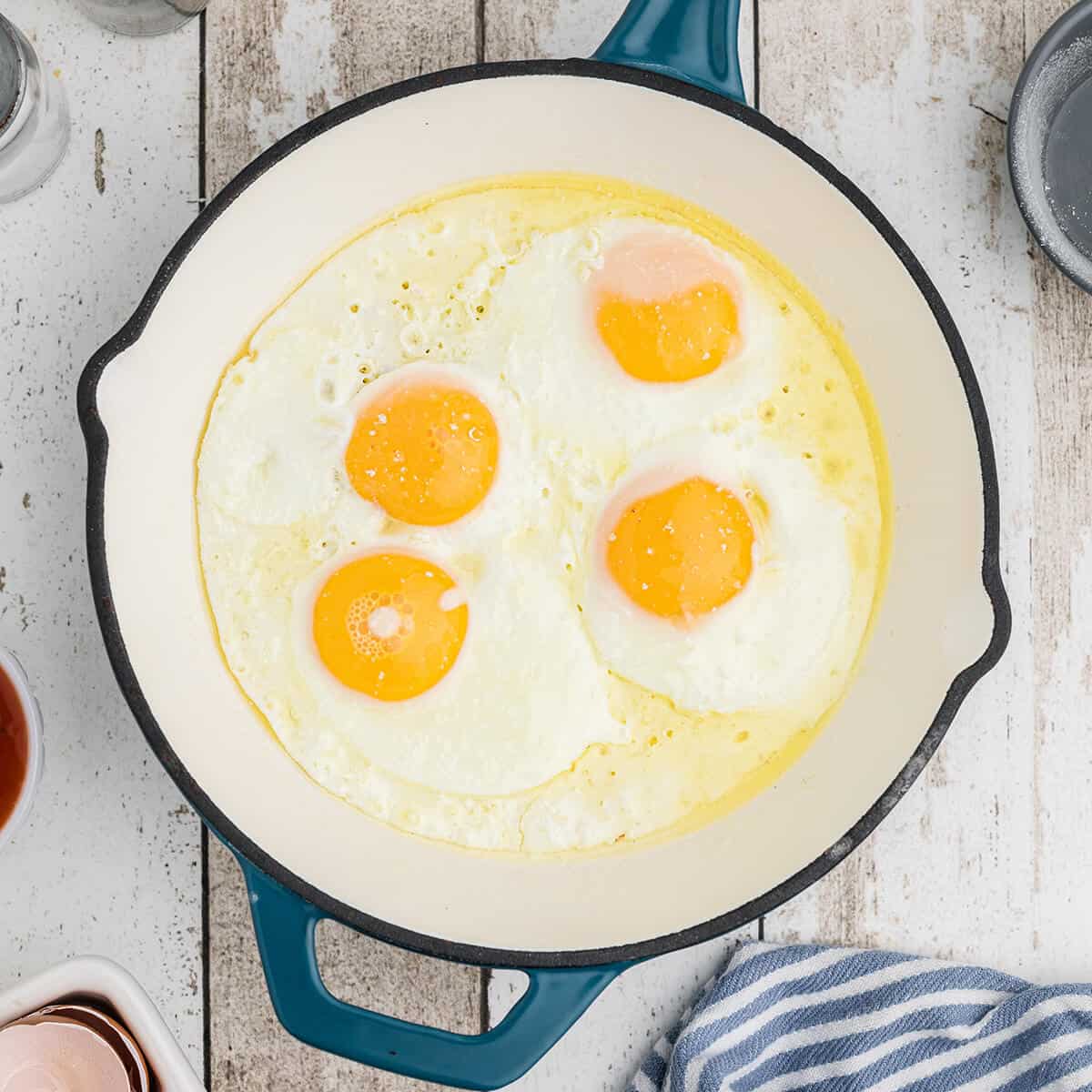 Eggs frying in butter in a skillet.