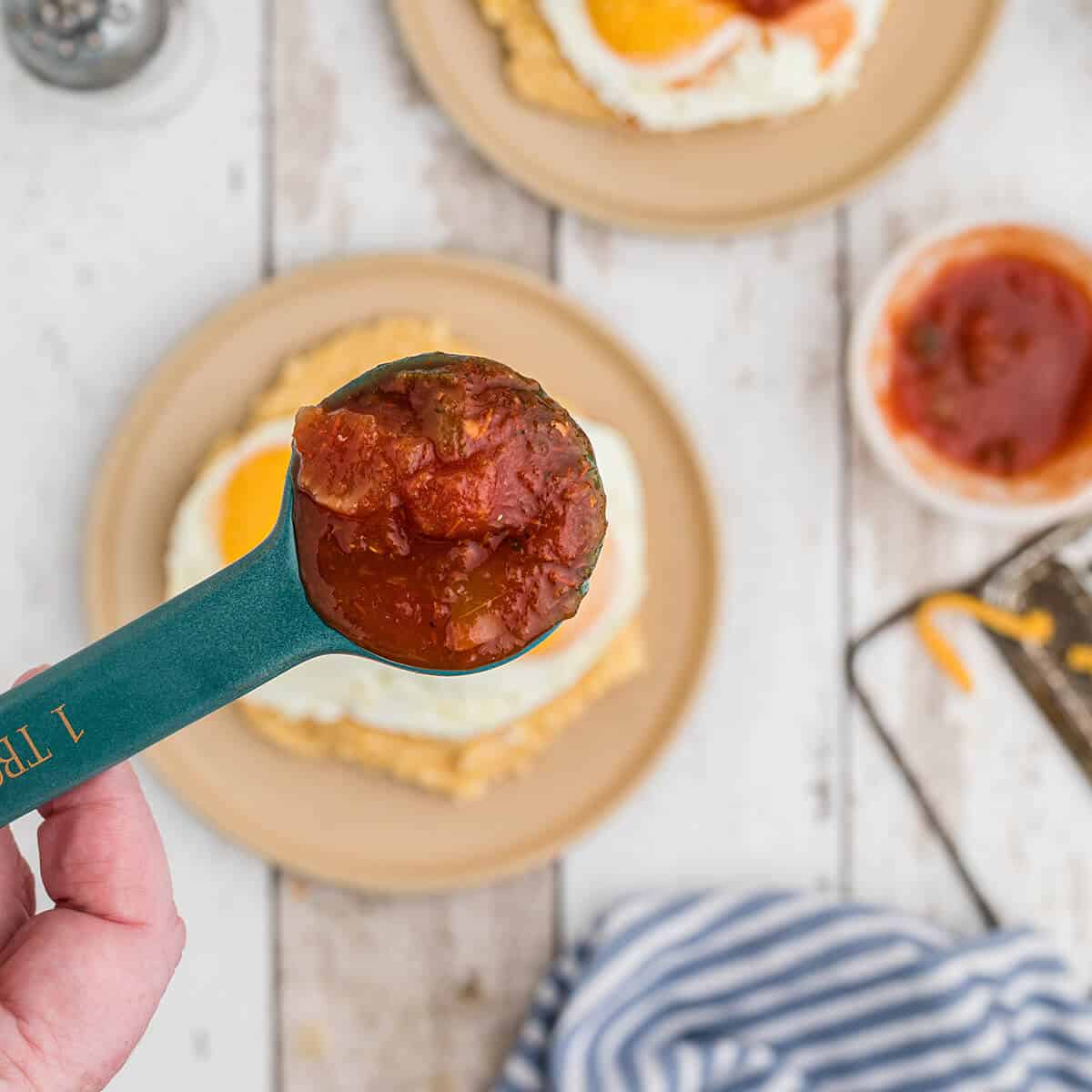 Topping fried eggs with salsa.