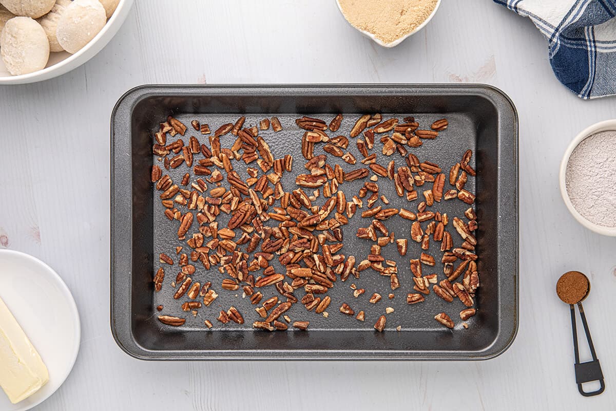 9x13 baking pan with chopped pecans sprinkled in the bottom.