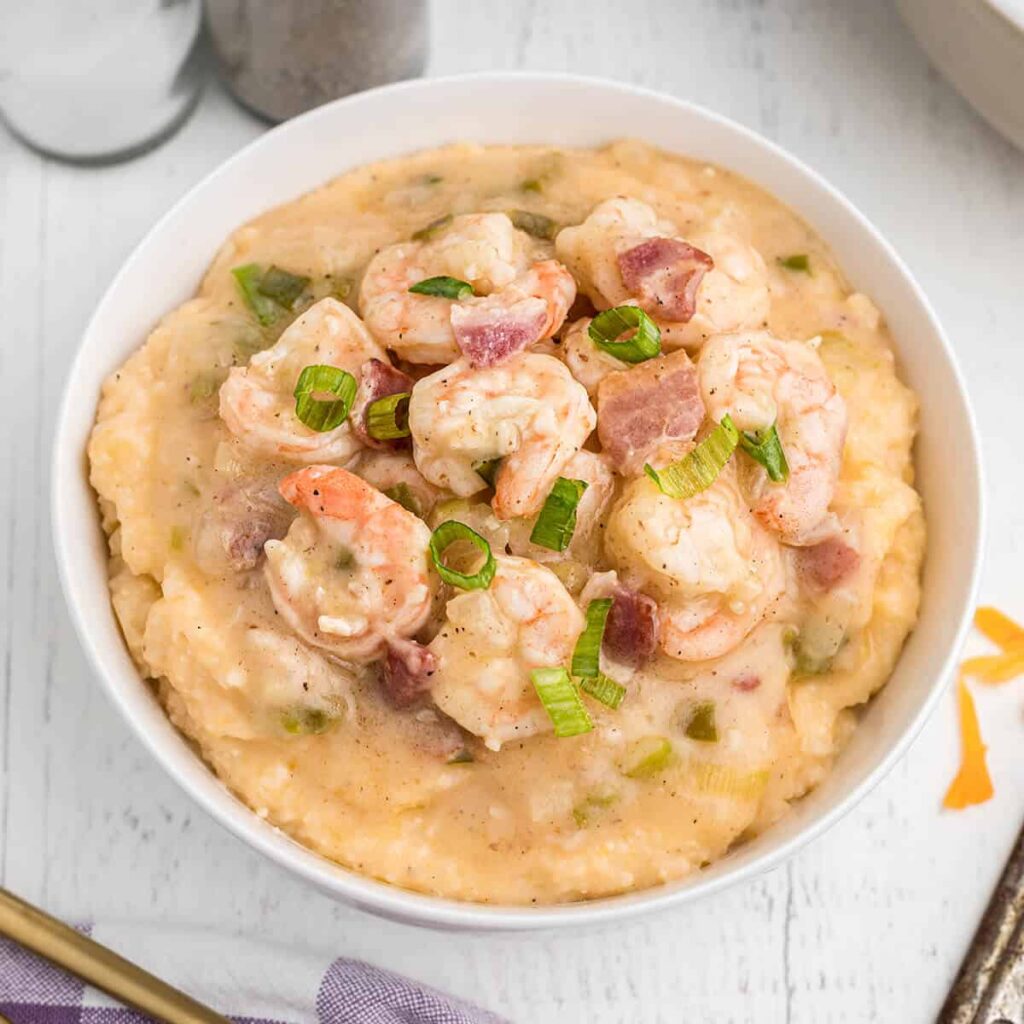 A serving a shrimp and grits in a white bowl.