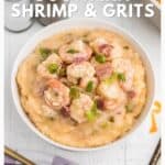 Bowl of shrimp and grits topped with green onions, with a fork on the side and website text below.