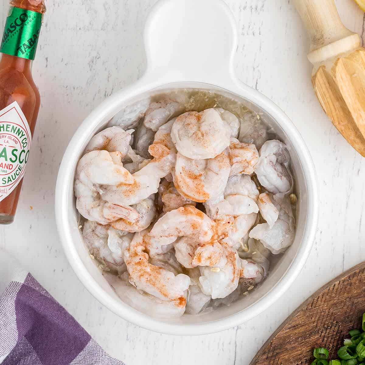 Shrimp with lemon juice and Tabasco in a white bowl.