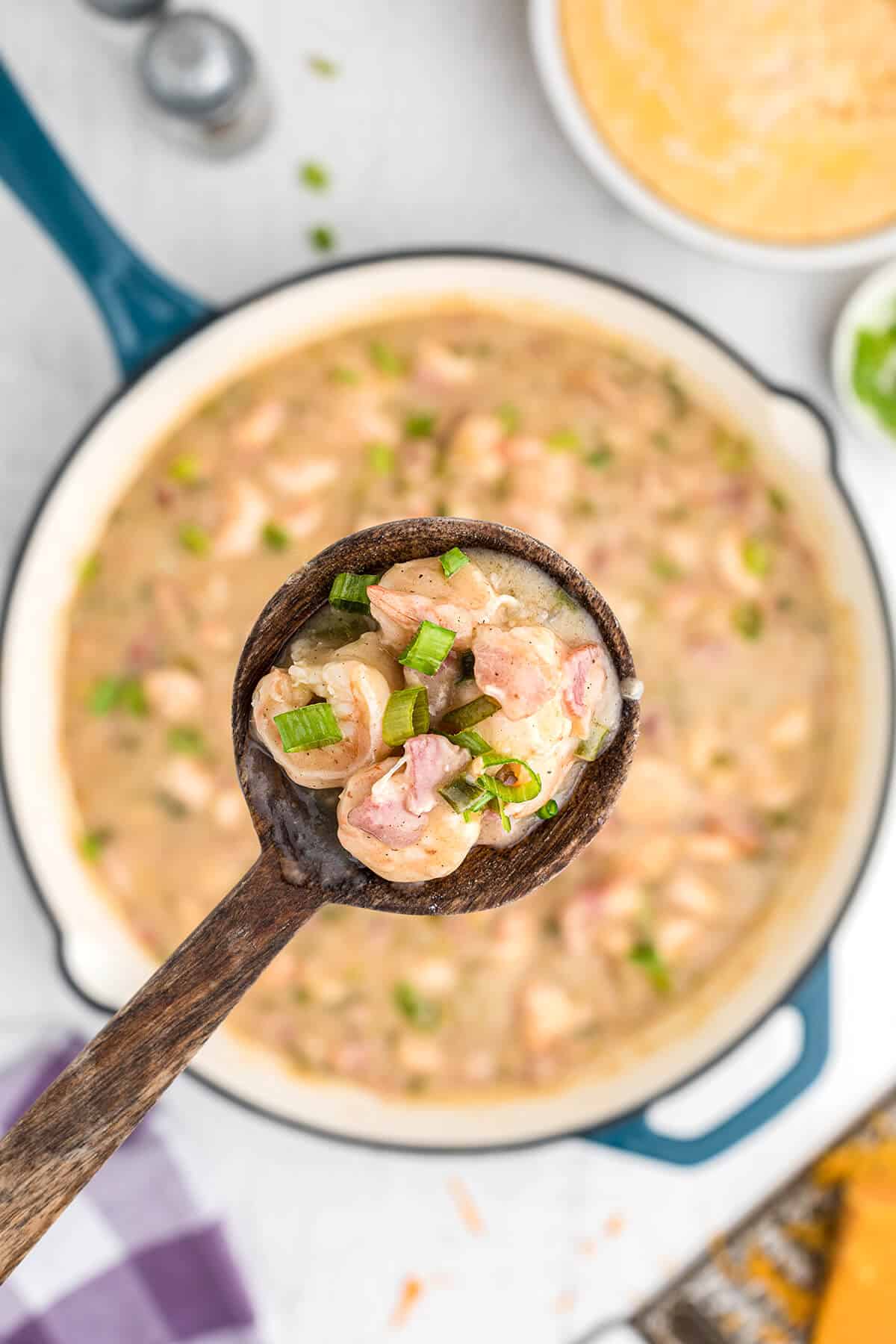 A wooden spoon holding a bite of shrimp and grits.
