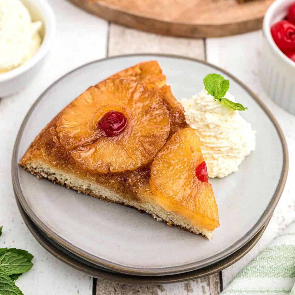 A slice of pineapple upside down cake on a serving plate.