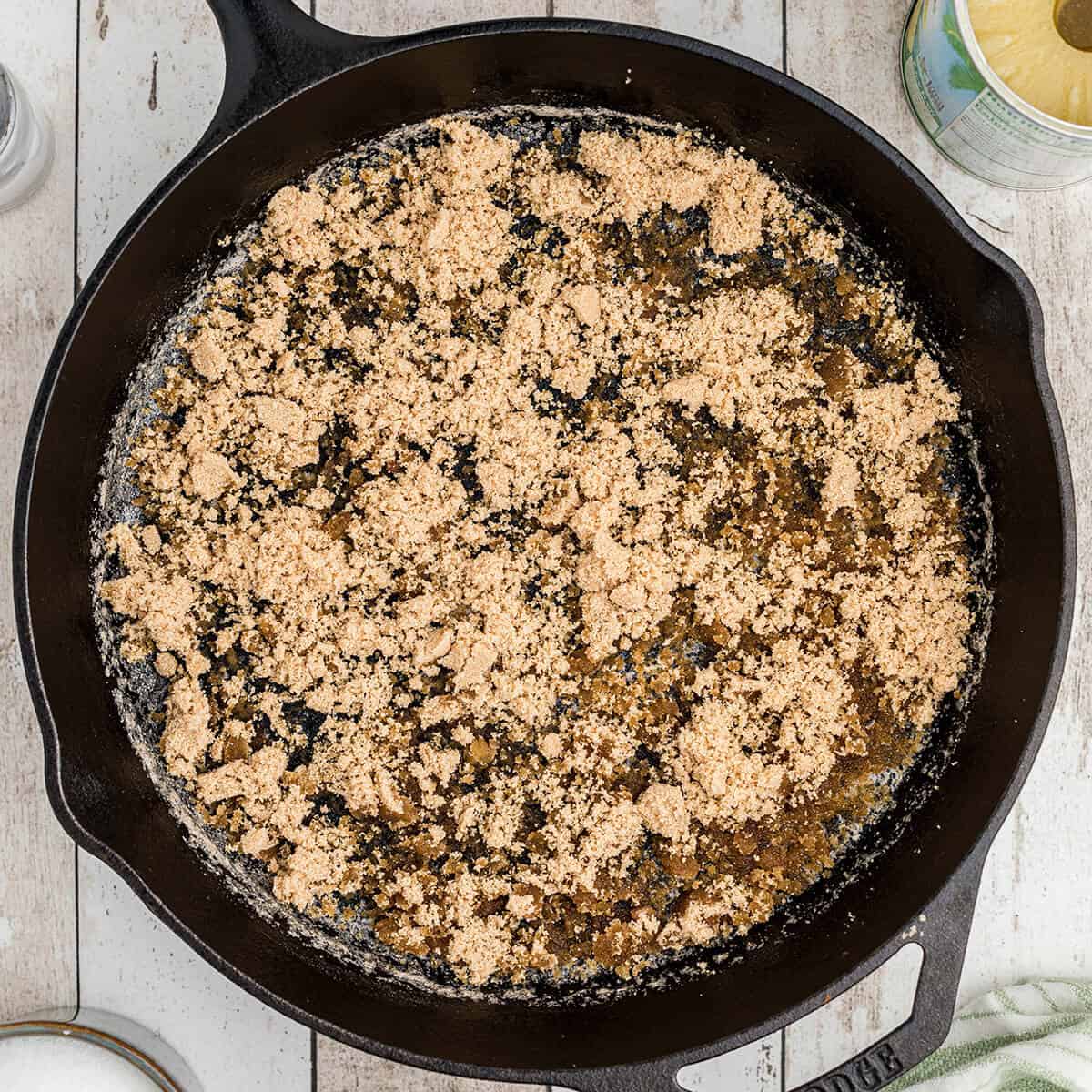 Brown sugar spread over melted butter in a cast iron skillet.