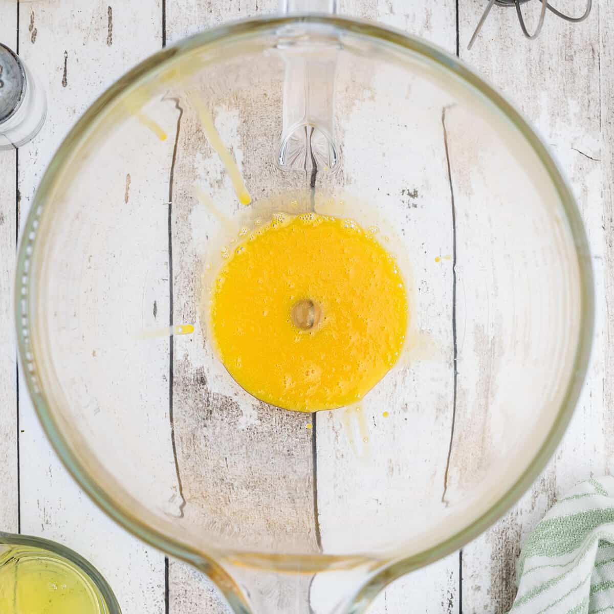 Beaten egg yolks in a glass bowl.
