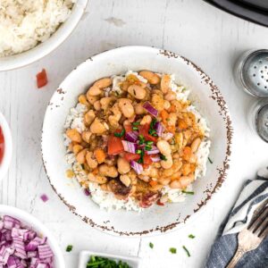 A serving of white beans garnished with tomato and onion.