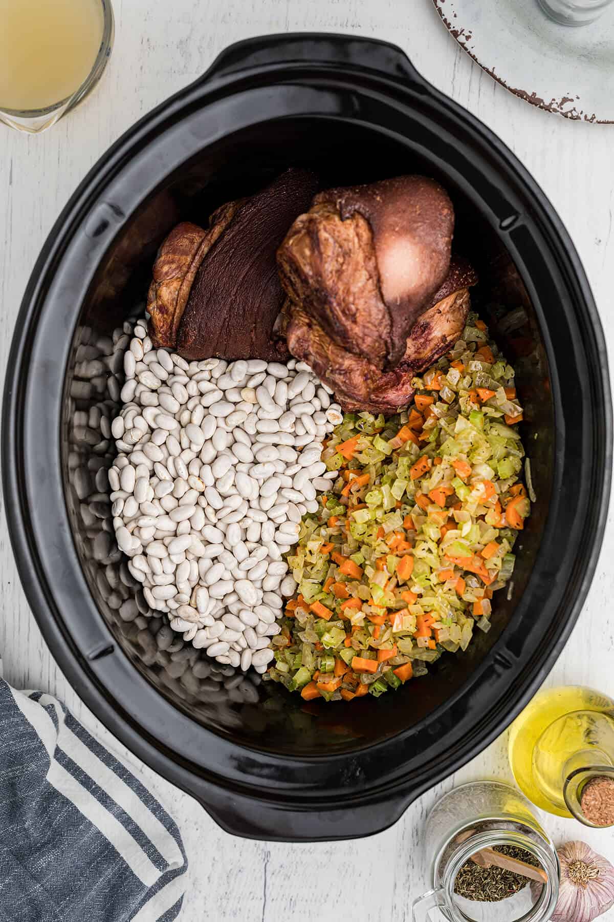 Sauteed vegetables, dried beans, and ham hocks in a slow cooker.