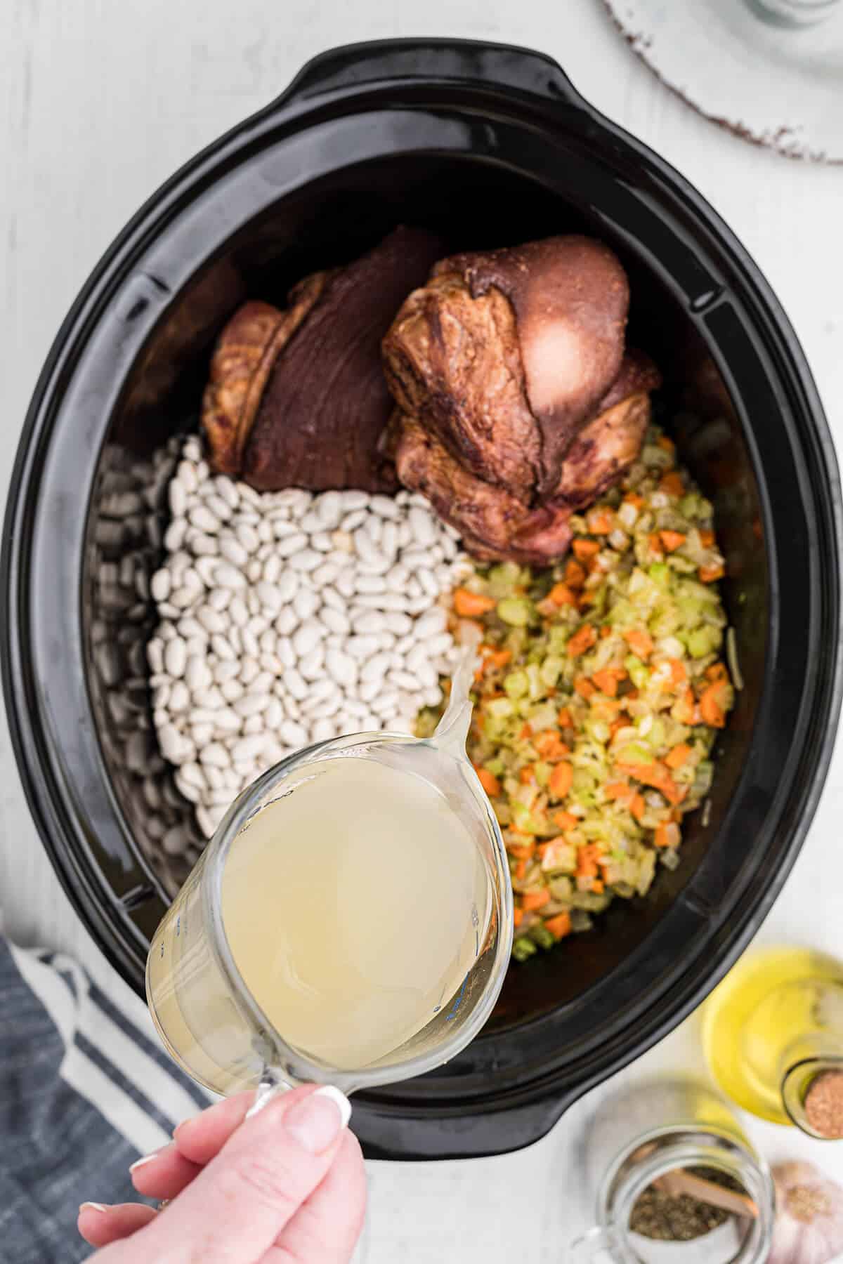 Pouring chicken stock into the slow cooker.