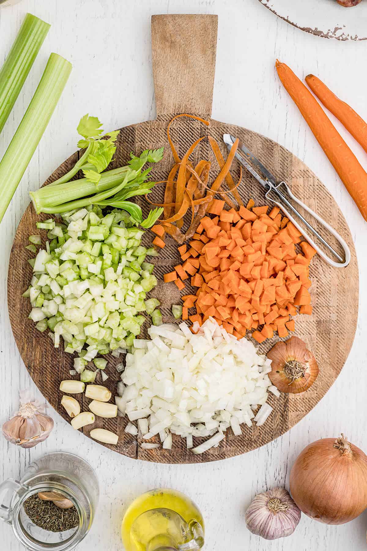 Diced celery, carrot, onion, and garlic on a wooden board.