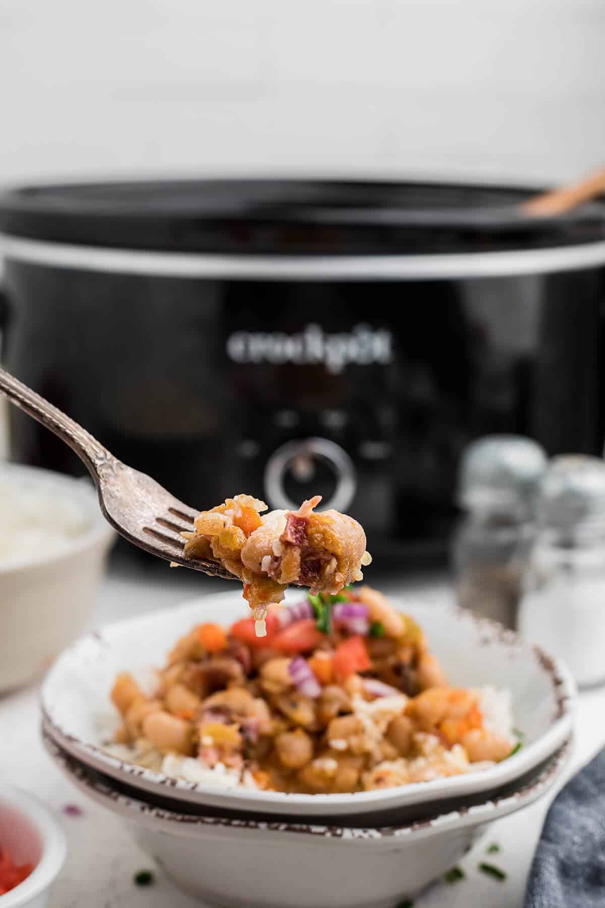 A serving of beans with garnish in a white bowl.