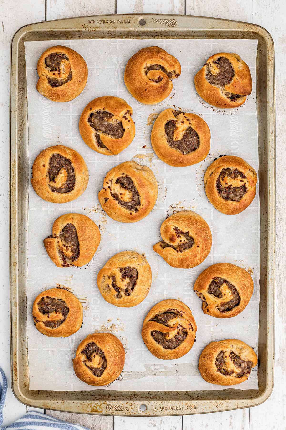 Baked sausage swirls on a baking sheet.