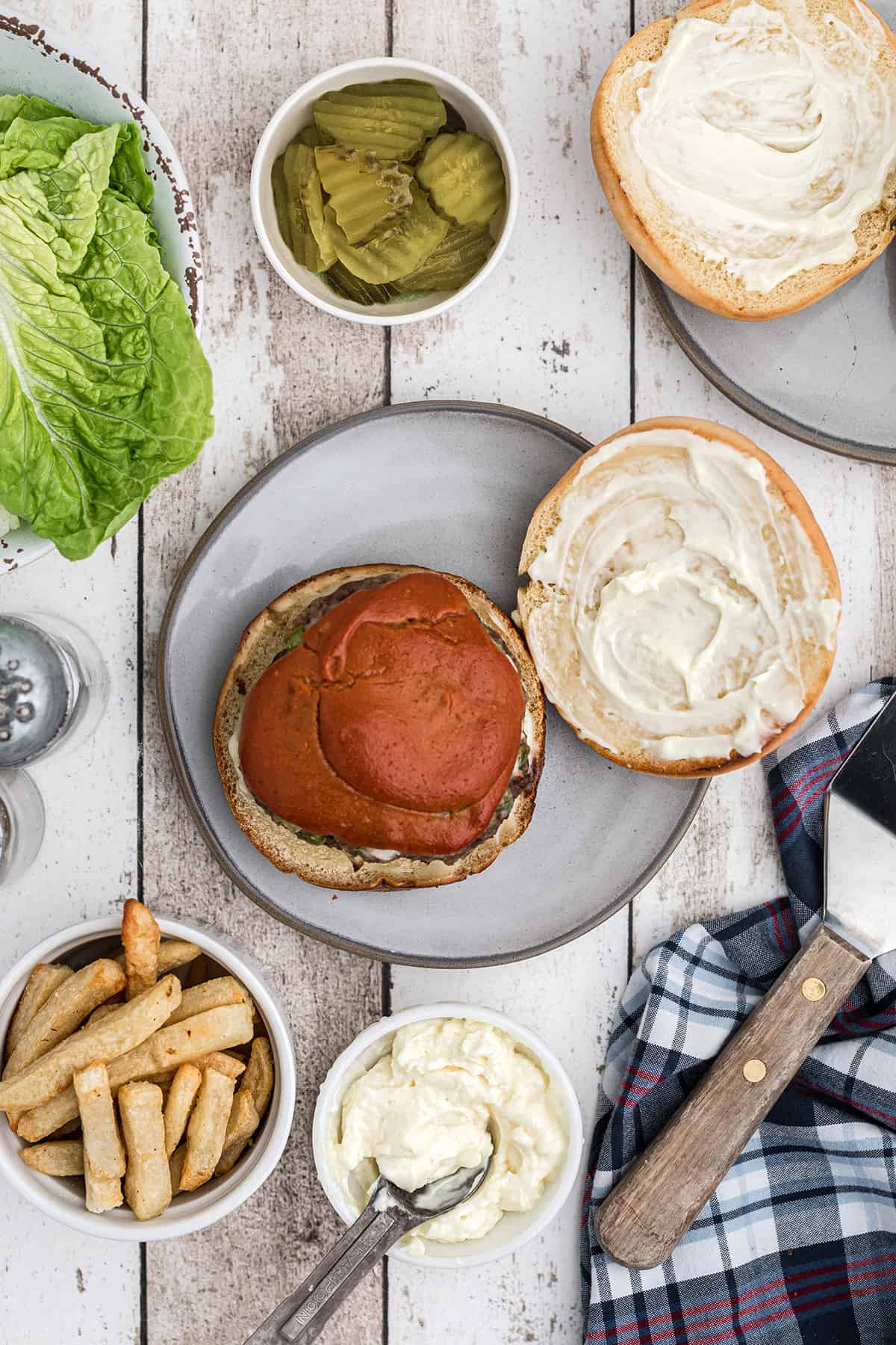 Cooked burger added to a bun on a plate.