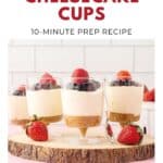 Three no-bake cheesecake cups topped with berries, with whole strawberries and a spoon in front.