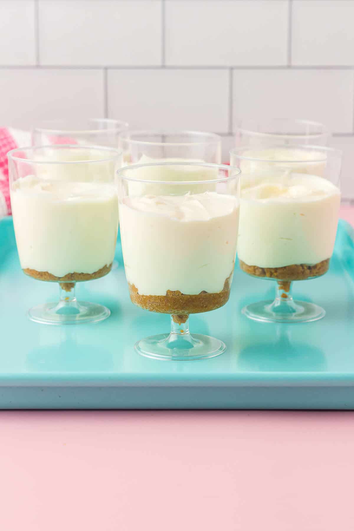 Dessert cups filled with graham cracker base and cream cheese mixture.