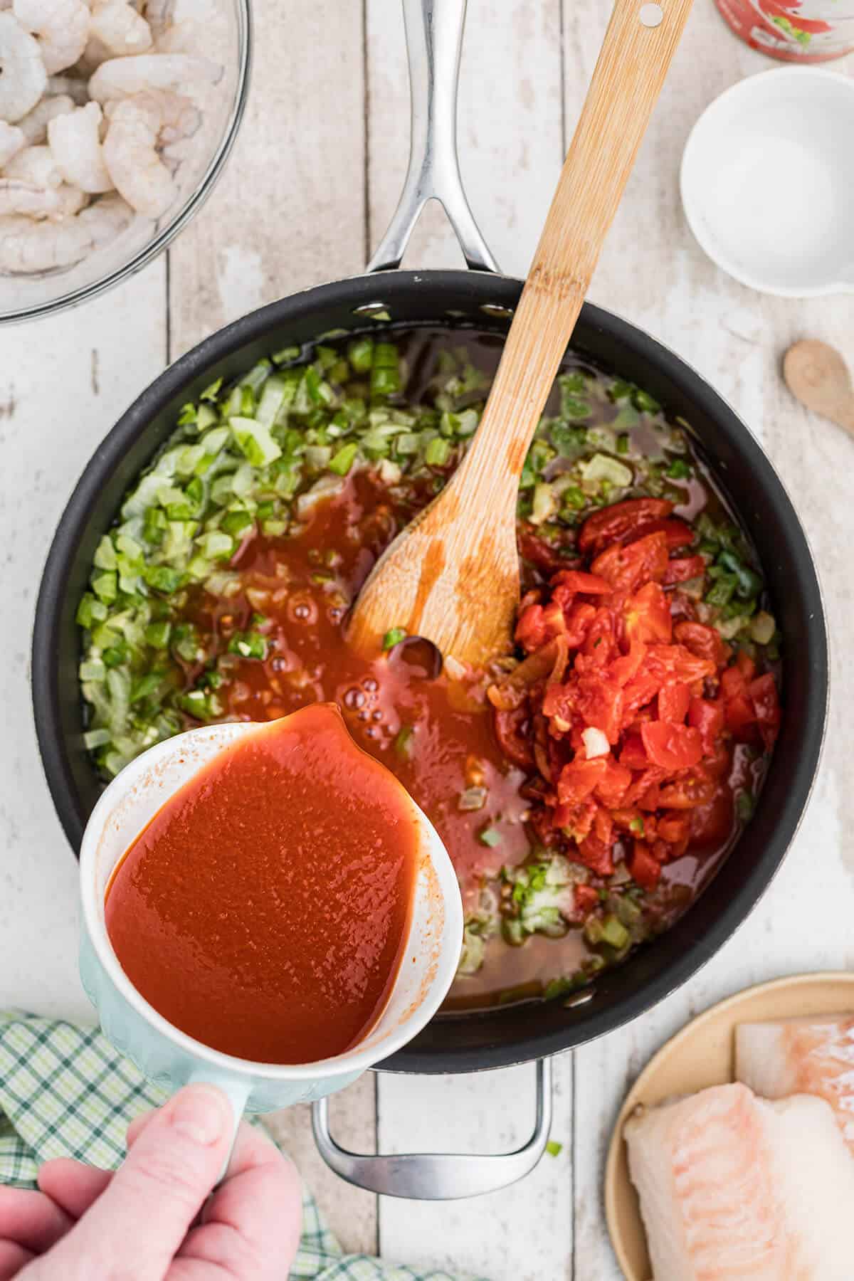 Adding V-8 juice to vegetables in a skillet.