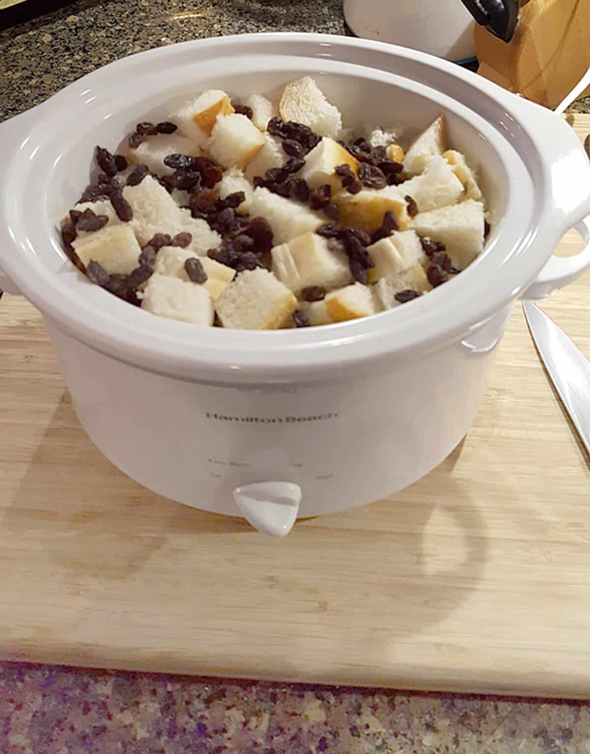 Bread cubes and raisins in a small slow cooker.