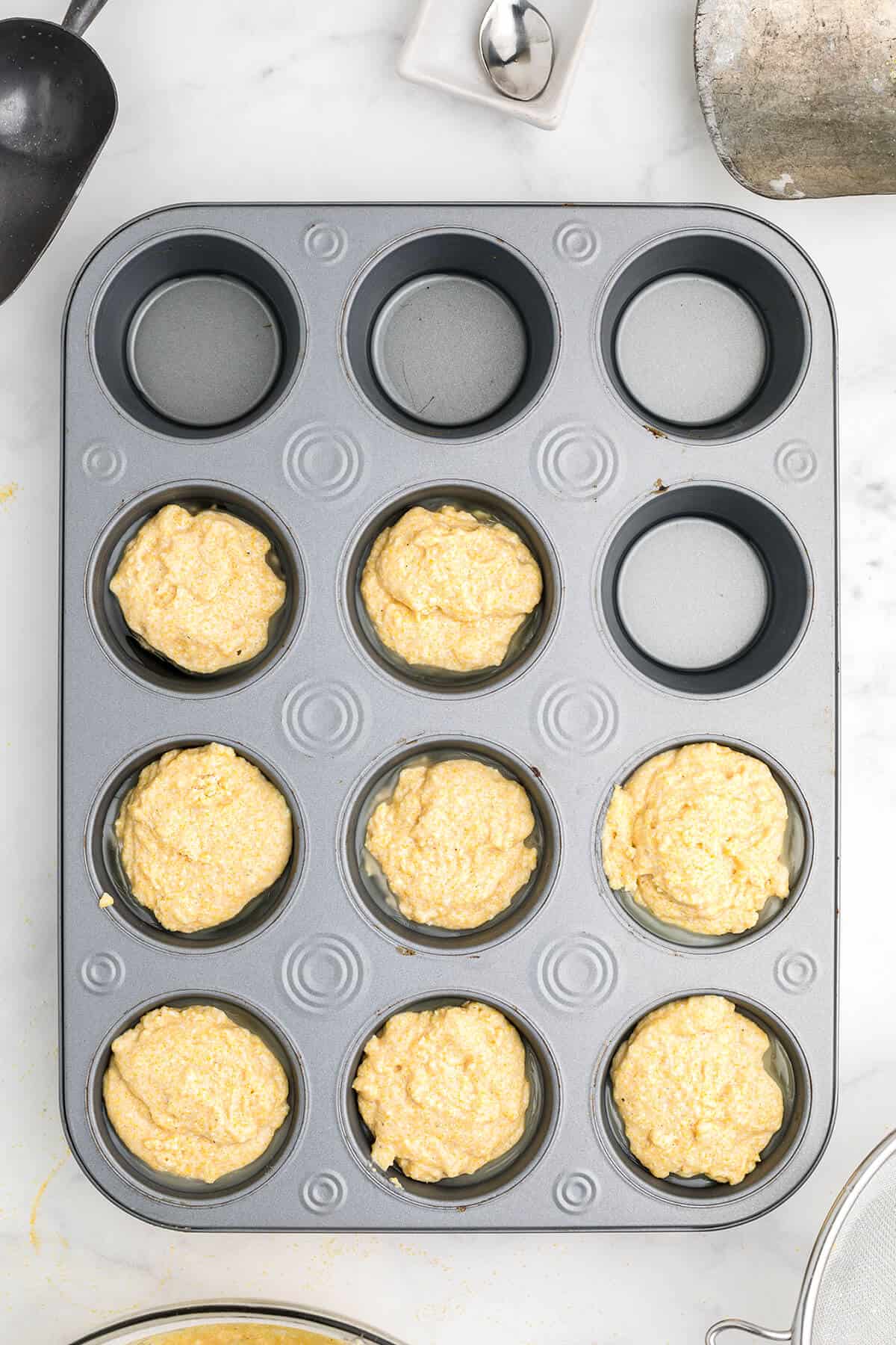 Muffin batter being added to muffin tin.