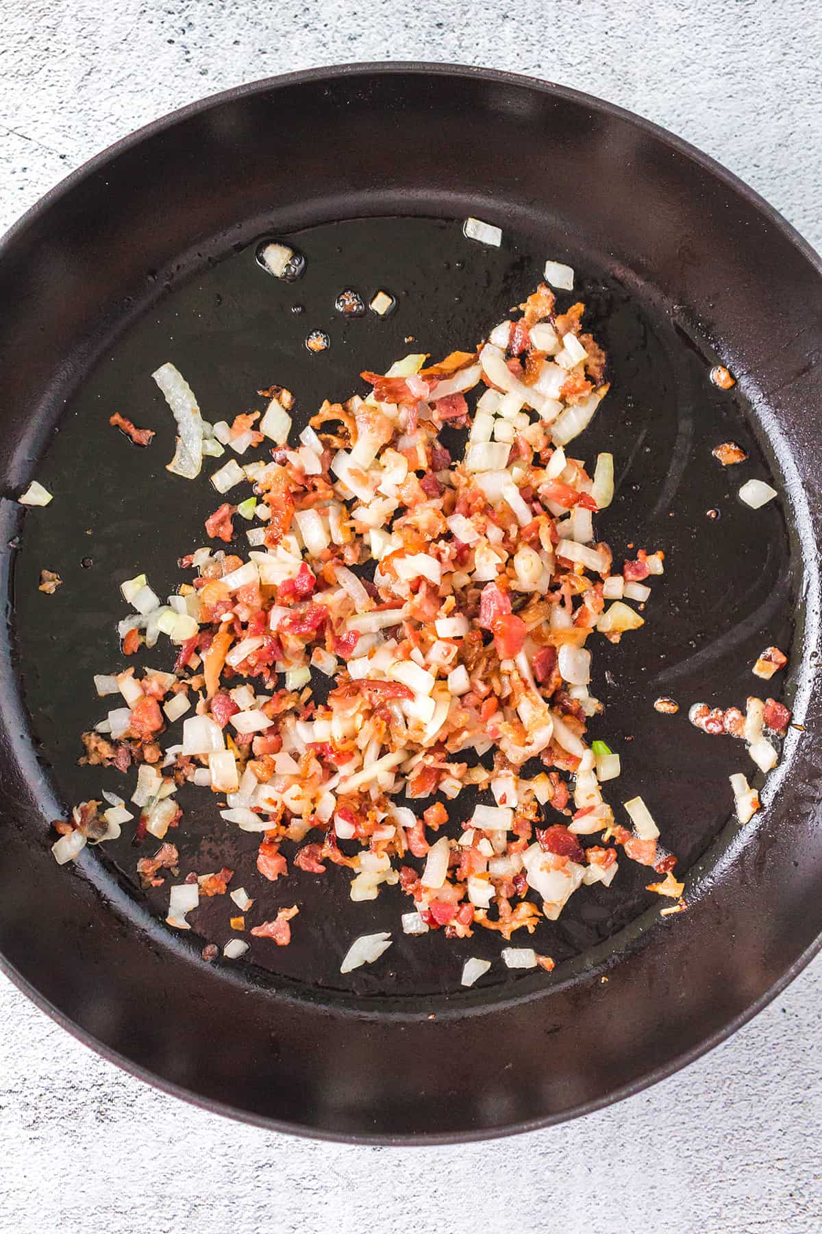 Onions and bacon cooking in a skillet.