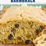 A sliced loaf of traditional Irish barmbrack bread with raisins on a wooden surface.
