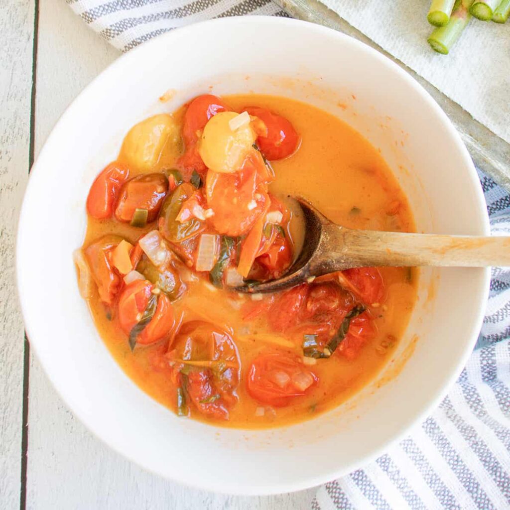 Burst cherry tomato sauce in a white bowl.