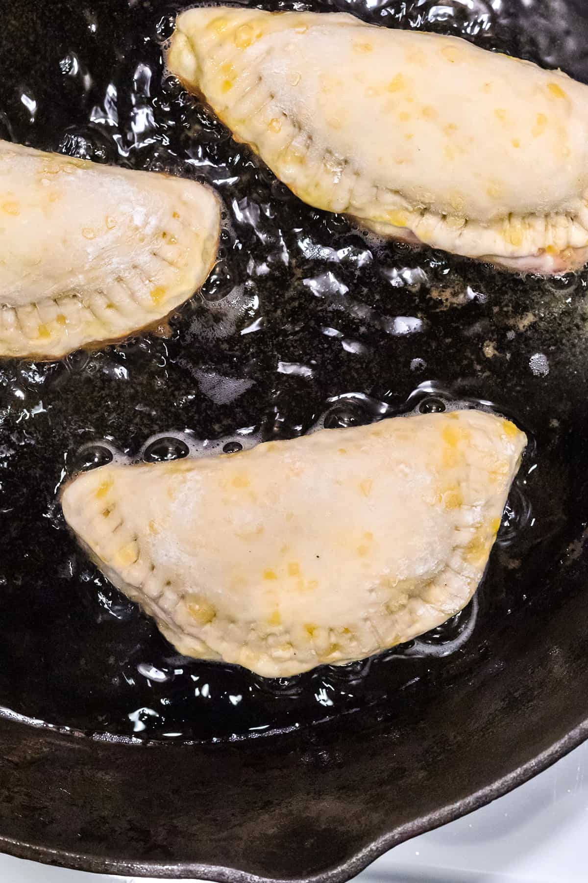Hand pies frying on the first side.