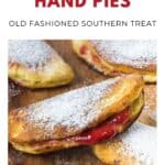 Golden fried cherry hand pies dusted with powdered sugar on a wooden surface.