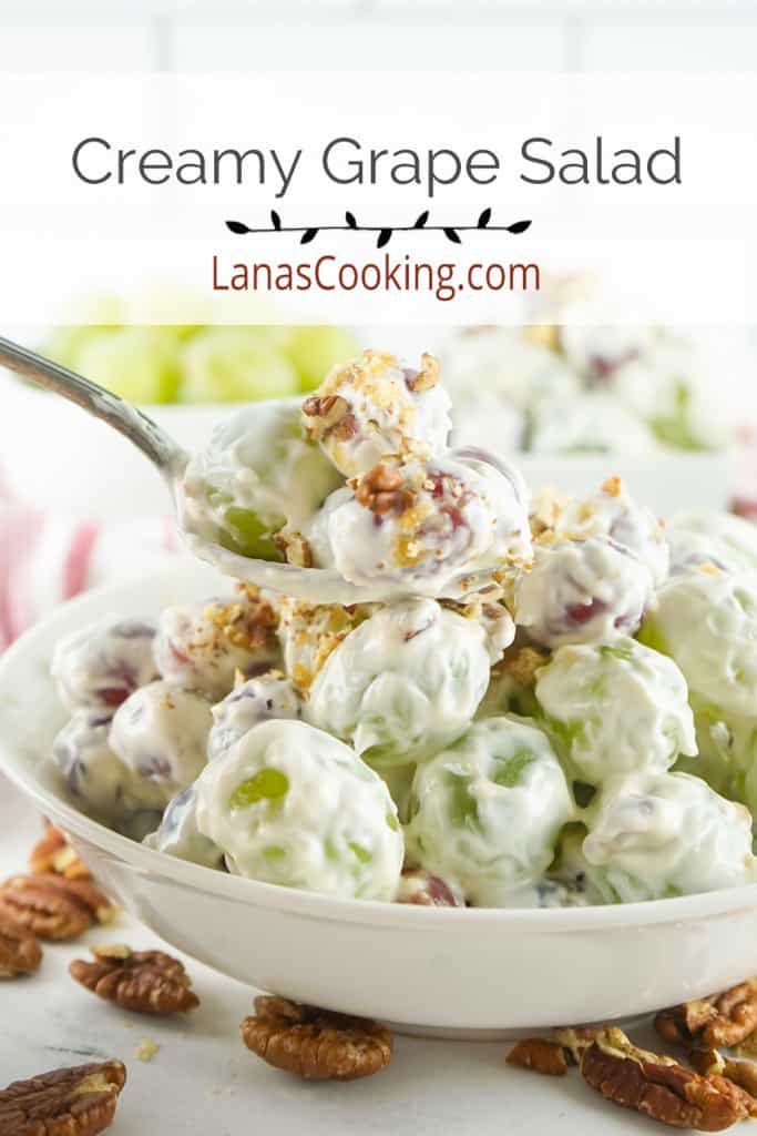 Creamy grape salad in a serving dish with a spoon.