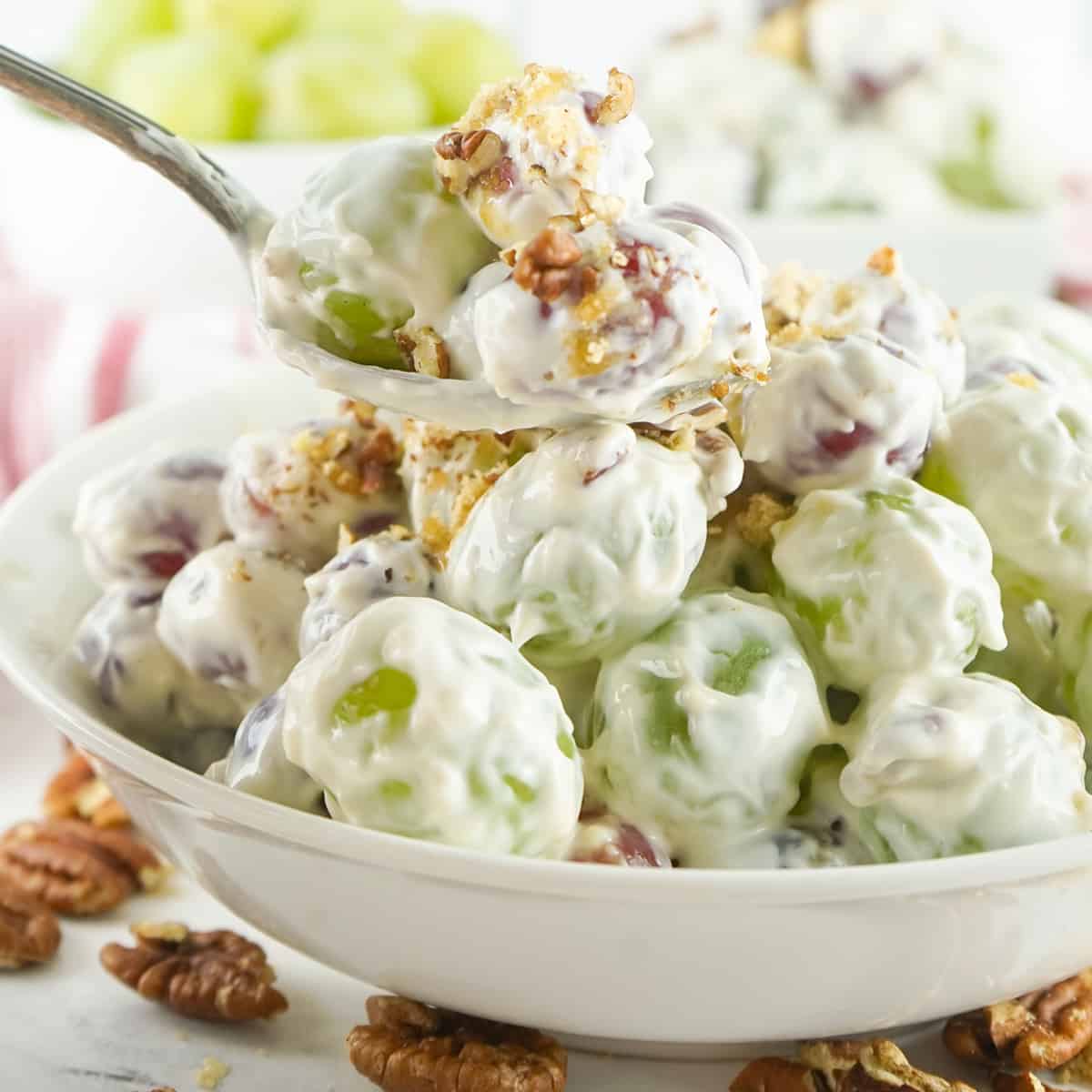 Creamy grape salad in a serving dish with a spoon.