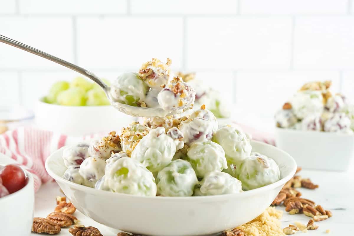 Creamy grape salad in a serving dish with a spoon.