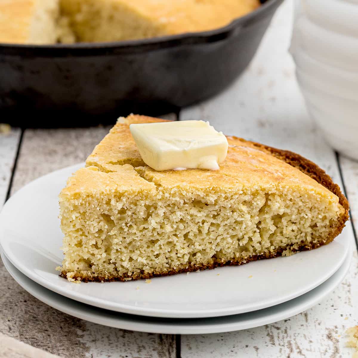 A slice of cornbread topped with a pat of butter.