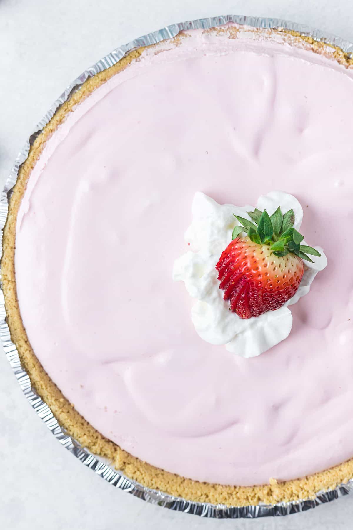 Finished pie with whipped cream and strawberry on top.