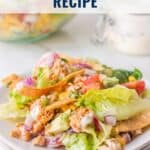 Plate of turkey taco salad with lettuce, tomato, onion, tortilla strips, and creamy dressing.