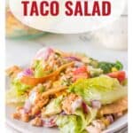 A plate of turkey taco salad with lettuce, tomatoes, red onion, and tortilla strips, topped with dressing.