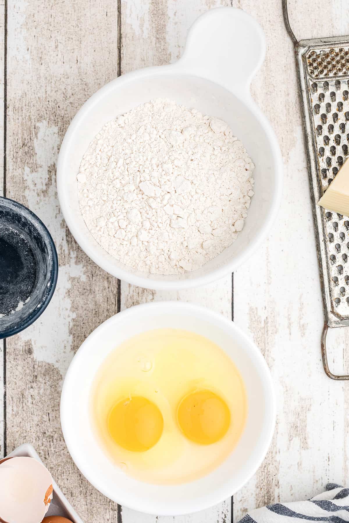 Two bowls holding flour and eggs.