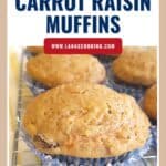 A close-up of low fat carrot raisin muffins in blue wrappers, cooling on a wire rack.