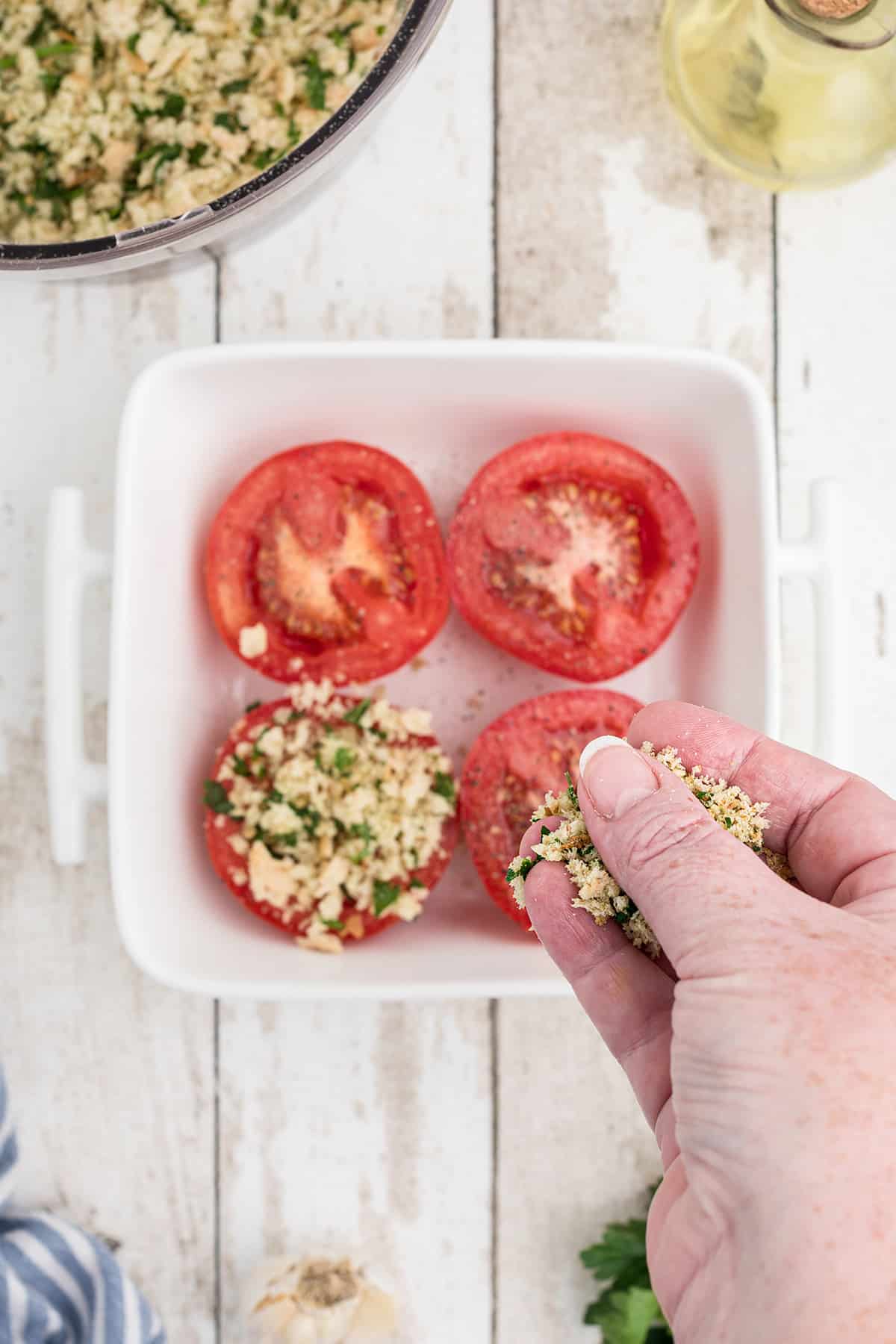 Adding breadcrumb mixture to each tomato.