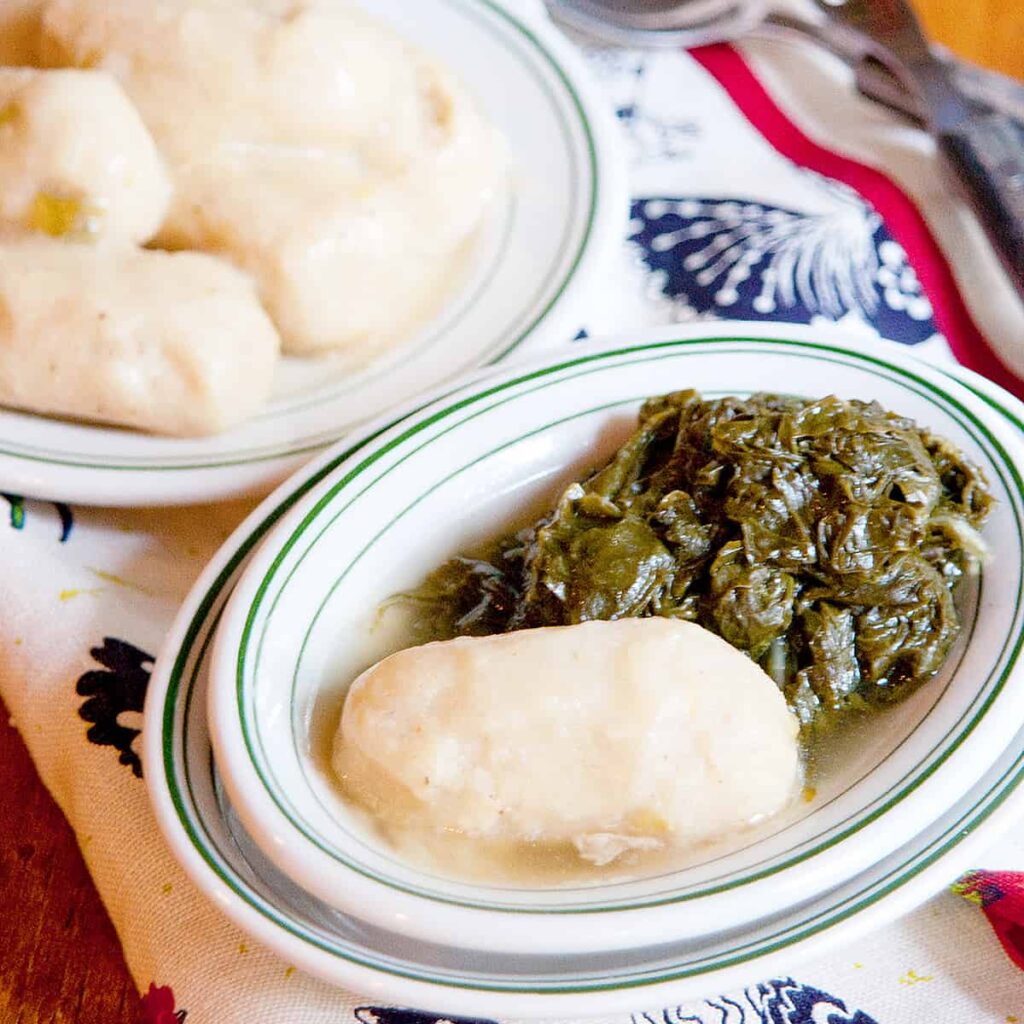 A corn dodger on a plate with turnip greens.