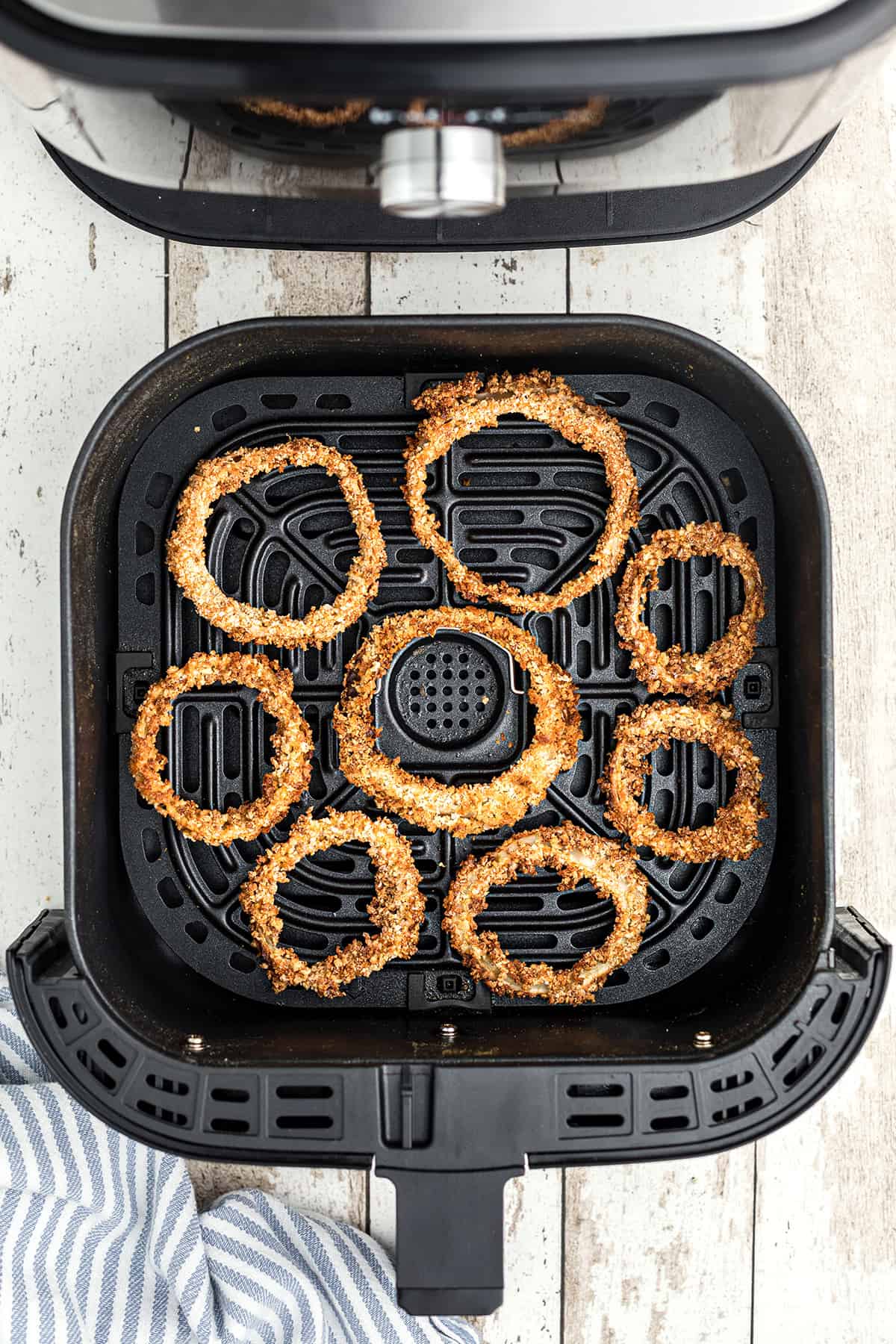 Finished onion rings in the air fryer basket.