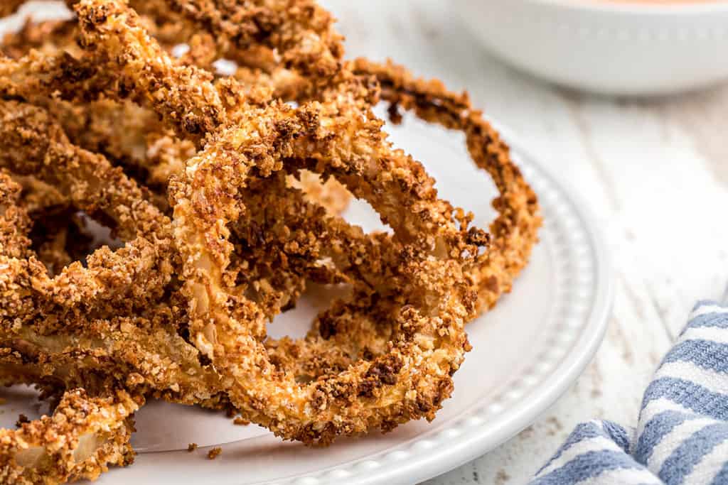 Finished onion rings on a white serving plate.