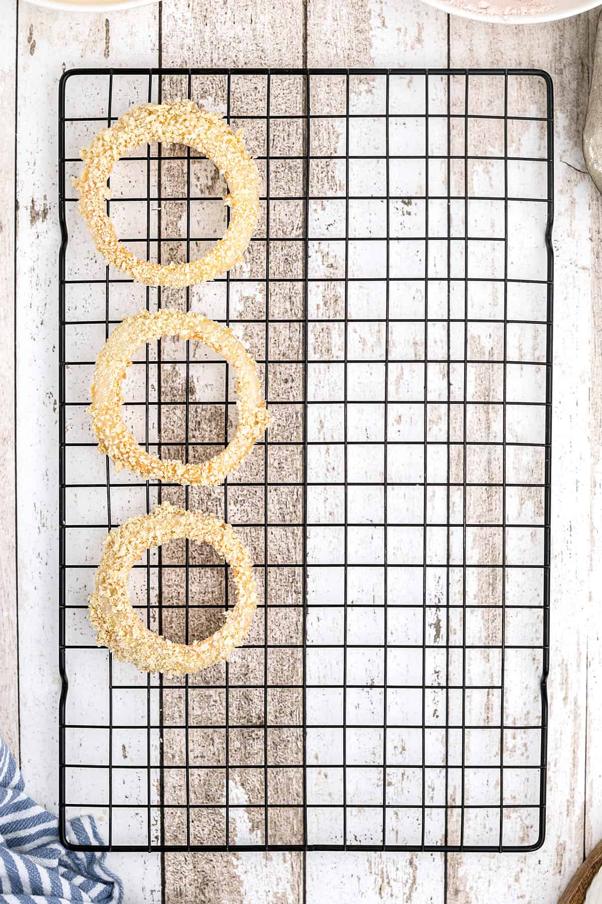 Prepped onion rings on a wire rack.