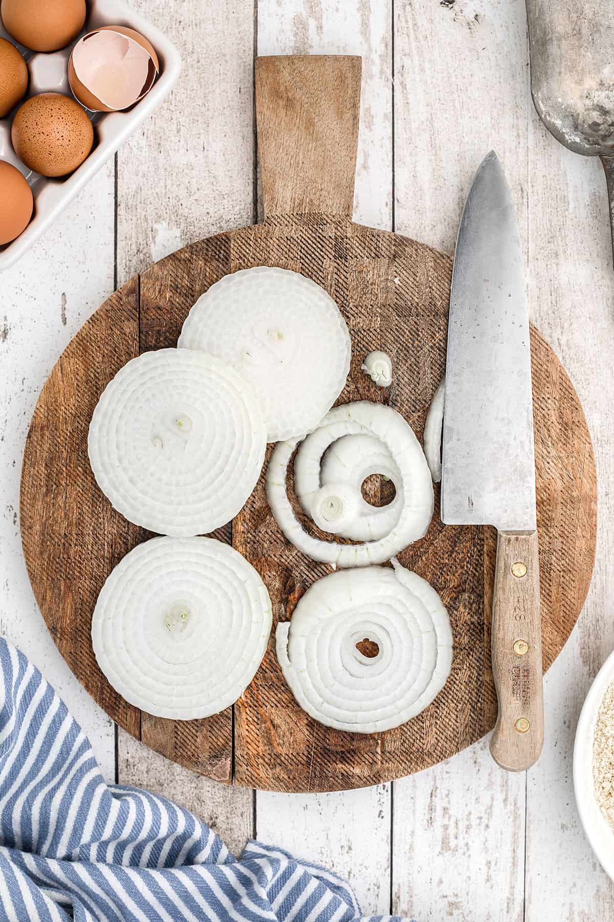 Sliced onion and knife on a wooden board.