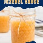 A glass jar filled with jezebel sauce, tied with twine, sits on a countertop with another jar in the background. Text reads: Sweet | Hot | Spicy JEZEBEL SAUCE.