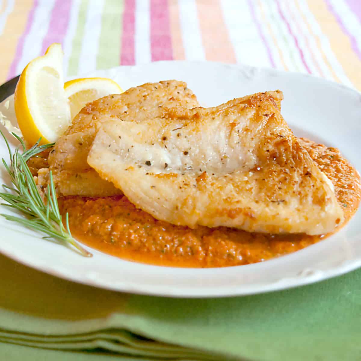 Pan fried fish on a bed of red pepper sauce.