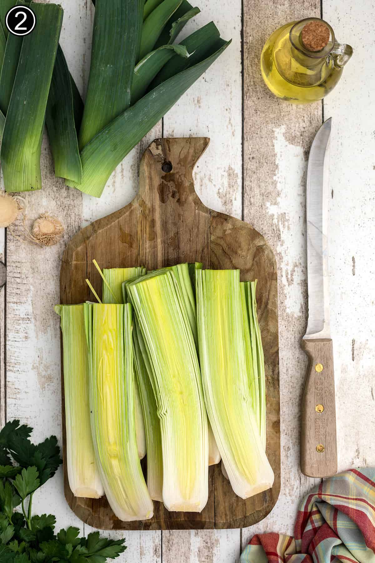 Leeks cut in half on a cutting board.