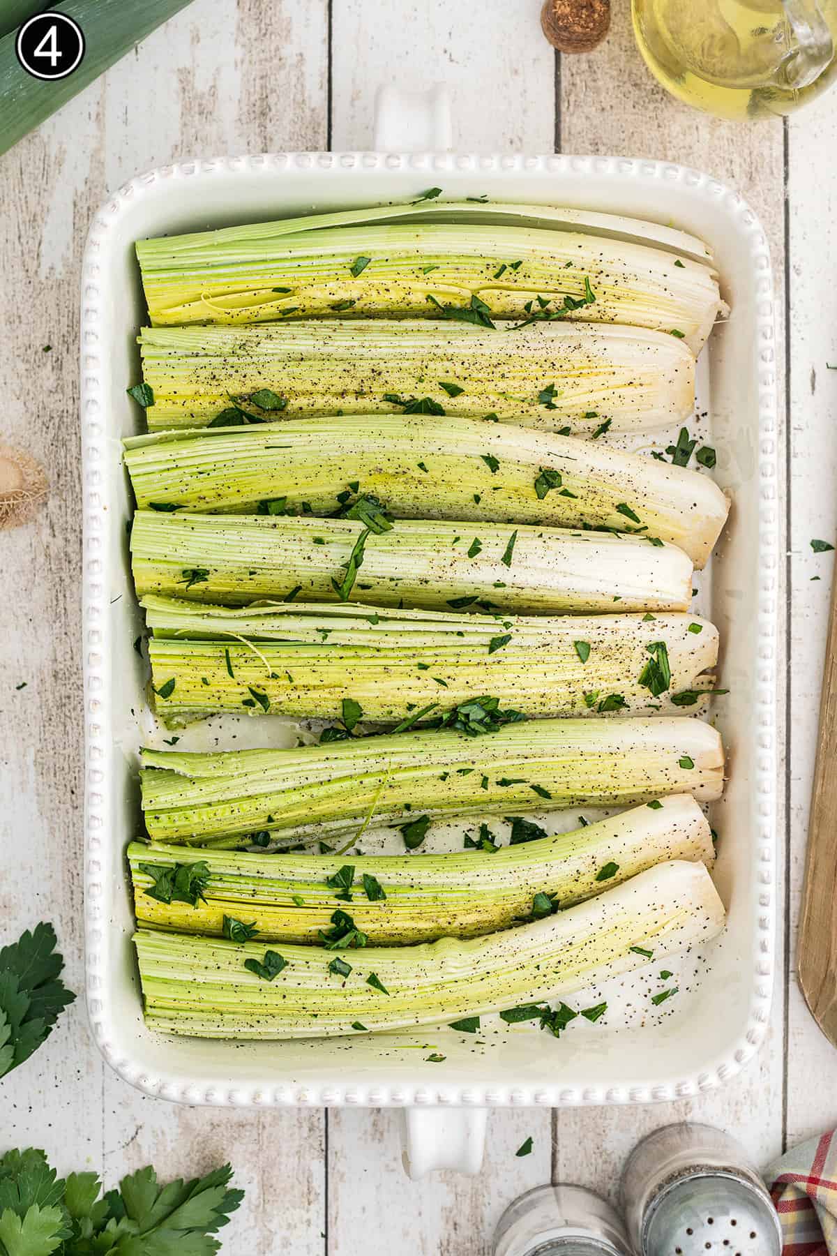 Seasonings added to leeks in a baking dish.