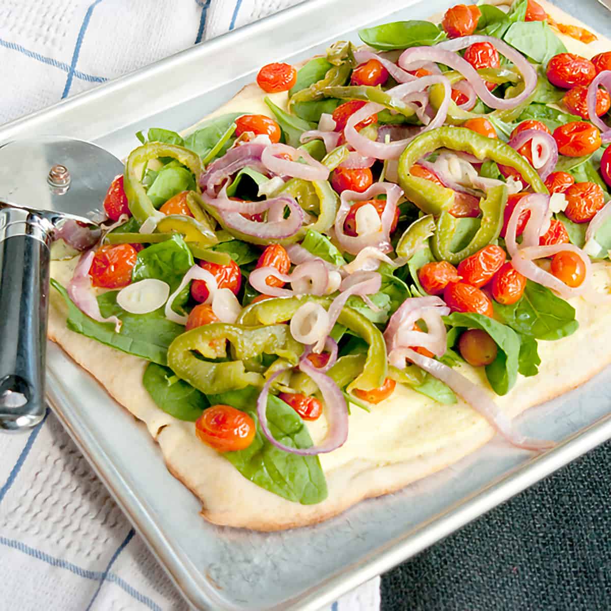 Roasted veggie pizza on a baking sheet.