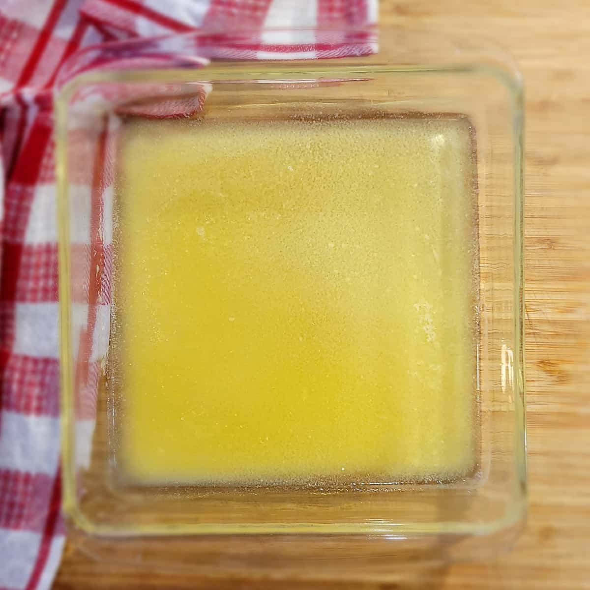 Melted butter poured into a square baking dish.